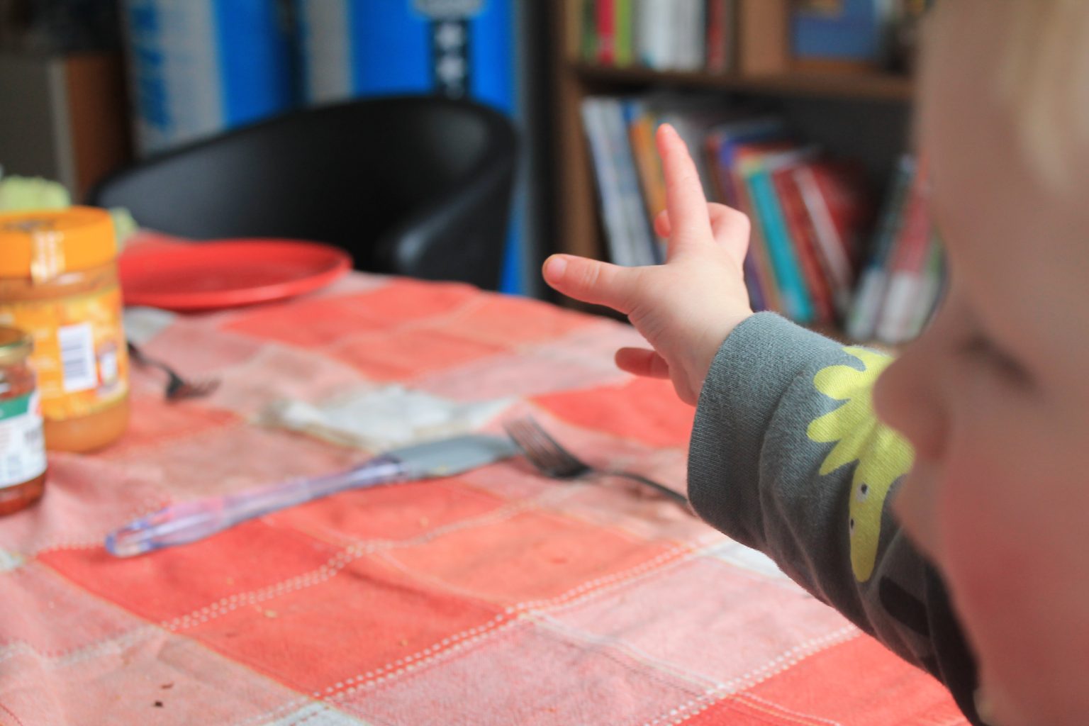 Kind steekt zijn hand uit naar pindakaas pot.